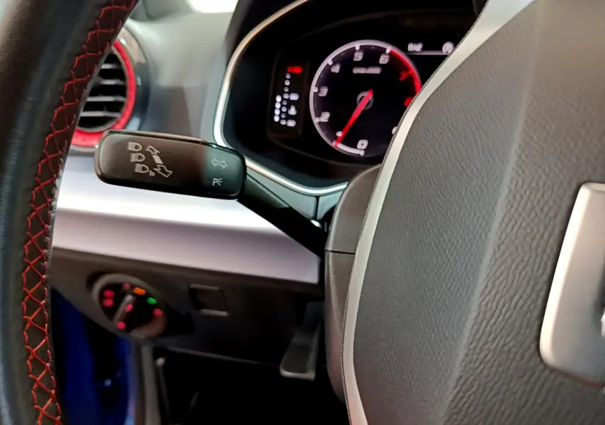 Gros plan sur le volant cuir avec surpiqûres rouges et tableau de bord numérique du SEAT Arona bleu 2022.