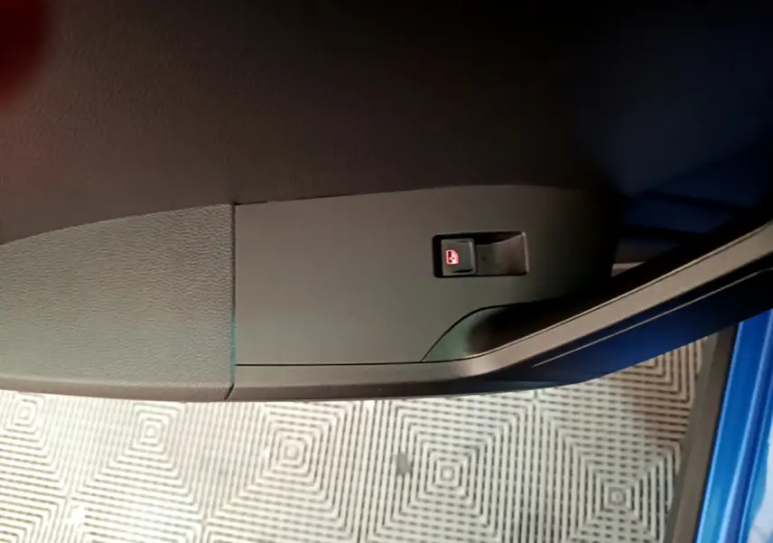 Gros plan sur le bouton de verrouillage des portes côté conducteur dans une SEAT Arona bleu 2022.