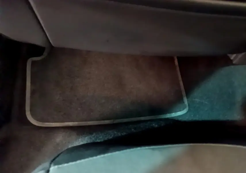 Tapis de sol marron sous le siège arrière d'un SEAT Arona bleu, vue intérieure côté passager arrière.