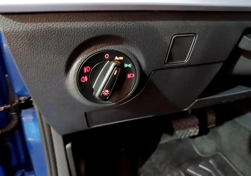Gros plan sur le bouton de commande des phares dans l'habitacle côté gauche d'un SEAT Arona bleu 2022.