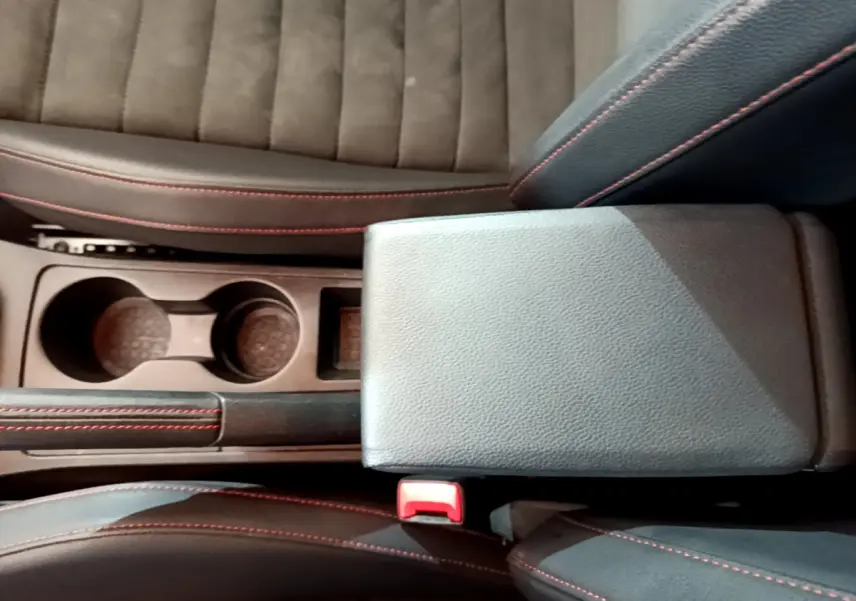 Vue plongeante sur la console centrale noire avec accoudoir et porte-gobelets du SEAT Arona bleu finition FR.