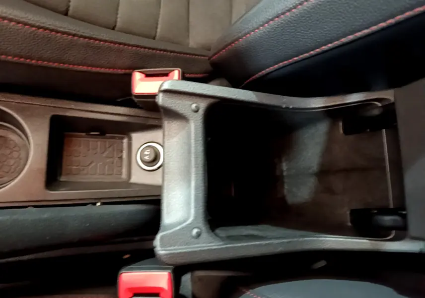 Vue plongeante sur l'accoudoir central ouvert et les sièges noirs avec surpiqûres rouges du SEAT Arona bleu 2022.