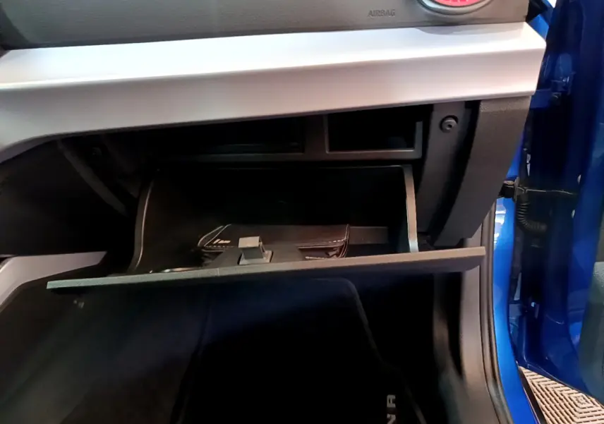 Gant de boîte à gants ouvert côté passager d'un SEAT Arona bleu 2022, montrant l'intérieur et une pochette noire.