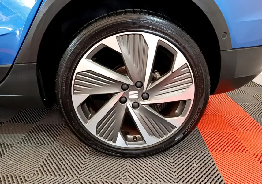 Gros plan sur la roue avant droite du SEAT Arona bleu 2022 avec jante alliage au design moderne.