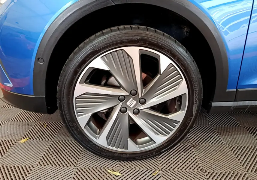 Gros plan sur la roue avant gauche avec jante spécifique du SEAT Arona bleu 2022, soulignant le design moderne.