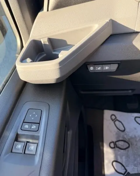 Détail intérieur côté conducteur du Renault Master blanc 2025, montrant les commandes de vitres et les boutons d'assistance sur la portière.