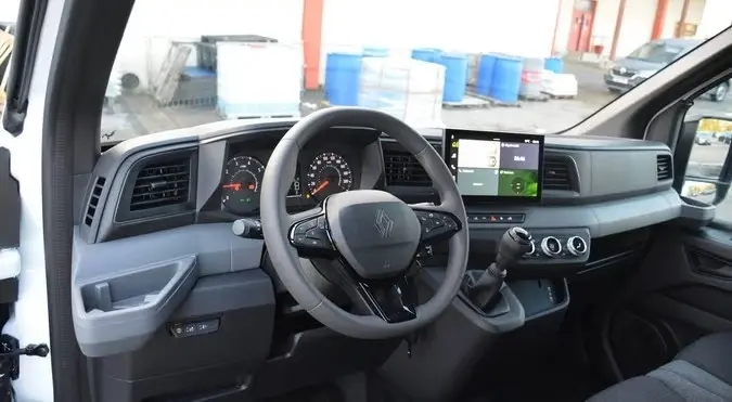 Vue intérieure du poste de conduite du Renault Master blanc 2025, avec volant multifonctions et écran tactile central.
