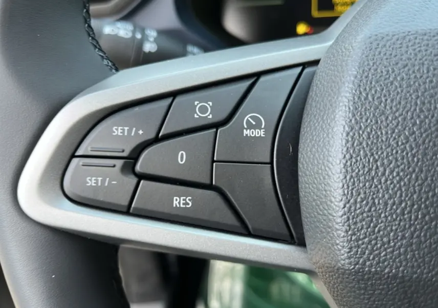 Gros plan sur les commandes noires du volant cuir du Dacia Bigster Hybrid 155 Expression Plus, détails des boutons de régulateur.