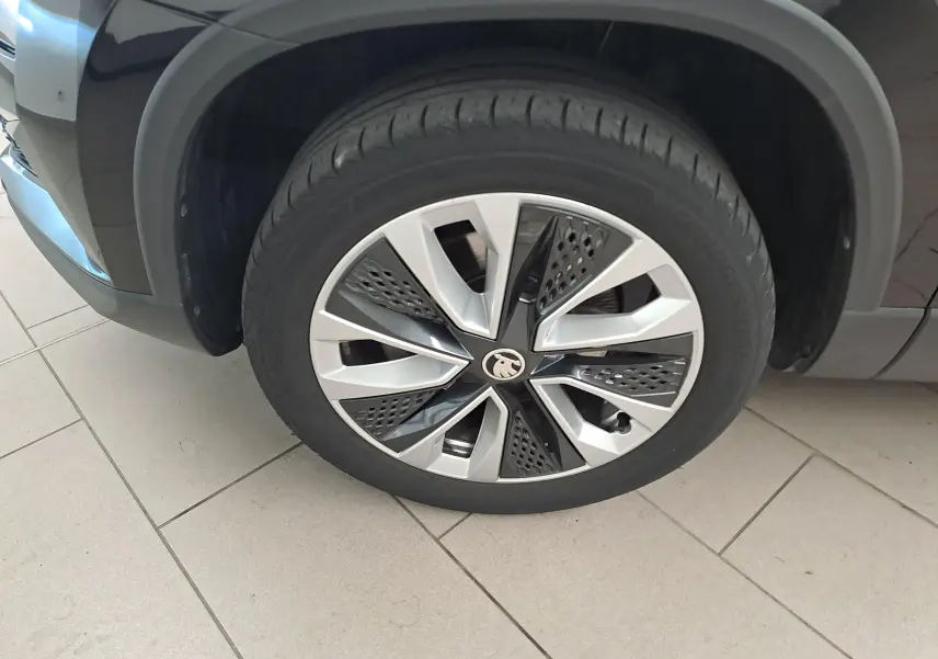 Gros plan sur la roue avant gauche du Skoda Karoq noir Magic Nacré, mettant en valeur la jante au design moderne.