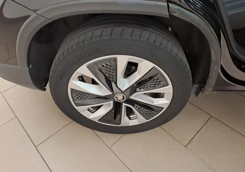 Gros plan sur la roue avant droite du Skoda Karoq noir Magic Nacré, mettant en valeur la jante alliage au design moderne.