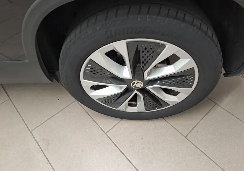 Gros plan sur la roue avant droite du Skoda Karoq noir Magic Nacré, mettant en valeur la jante au design moderne bicolore.