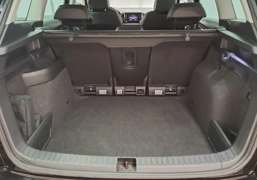 Coffre ouvert vu de l’arrière d’un Skoda Karoq noir Magic Nacré, montrant l’espace de chargement et les sièges arrière.