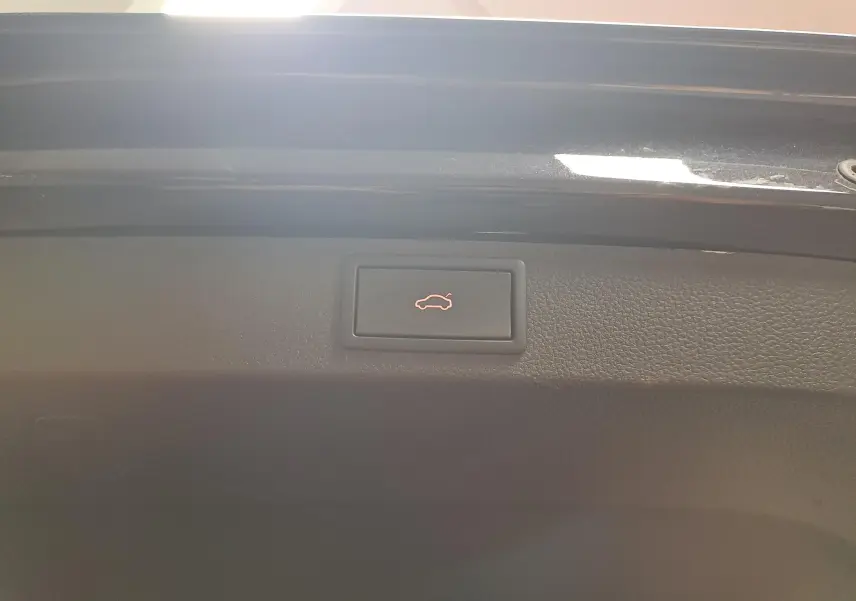 Bouton d'ouverture électrique du coffre sur la partie intérieure du hayon noir nacré d'un Skoda Karoq 2023.