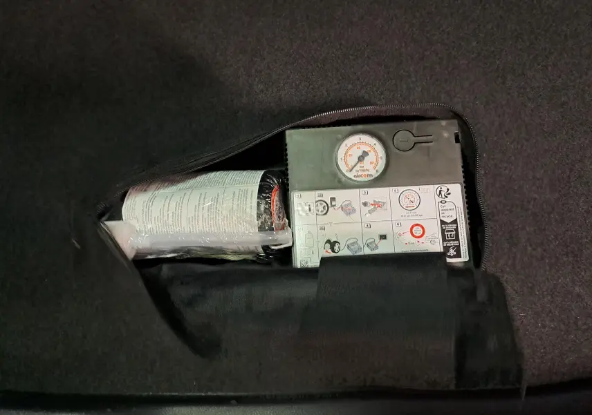 Gros plan sur le compresseur de pneu intégré dans le coffre du Skoda Karoq noir Magic Nacré 2023.