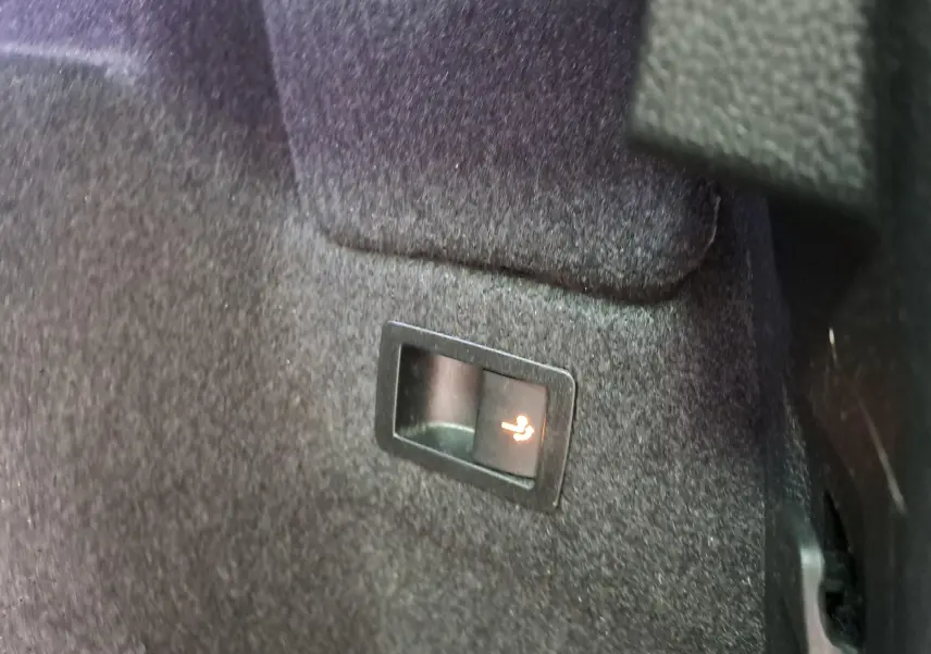 Gros plan sur le bouton d'inclinaison des sièges arrière dans le coffre du Skoda Karoq noir Magic Nacré 2023.