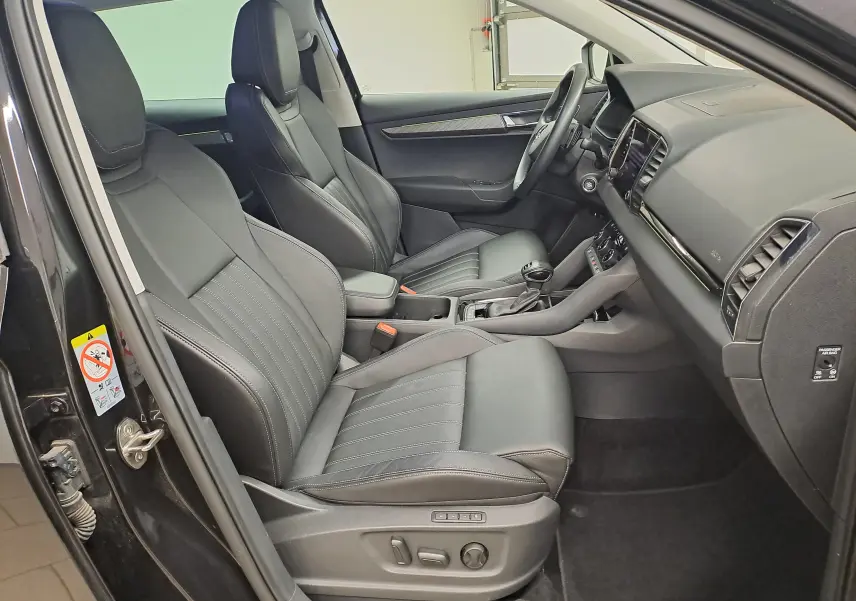 Vue intérieure côté conducteur du Skoda Karoq noir Magic Nacré, mettant en valeur les sièges cuir et la console centrale moderne.