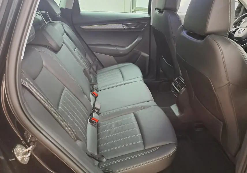 Vue intérieure côté gauche des sièges arrière en cuir noir du Skoda Karoq 2023 avec détails de surpiqûres blanches.
