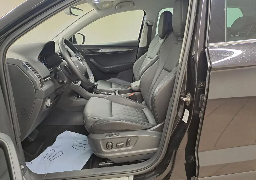 Vue intérieure côté conducteur du Skoda Karoq noir Magic Nacré 2023, avec sellerie cuir et réglages électriques des sièges.