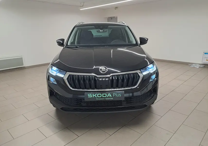 Vue frontale d'un Skoda Karoq 2023 noir Magic Nacré avec phares LED allumés dans un showroom.