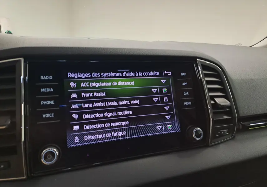 Écran central du Skoda Karoq 2023 montrant les réglages des aides à la conduite, avec interface noire et texte blanc.