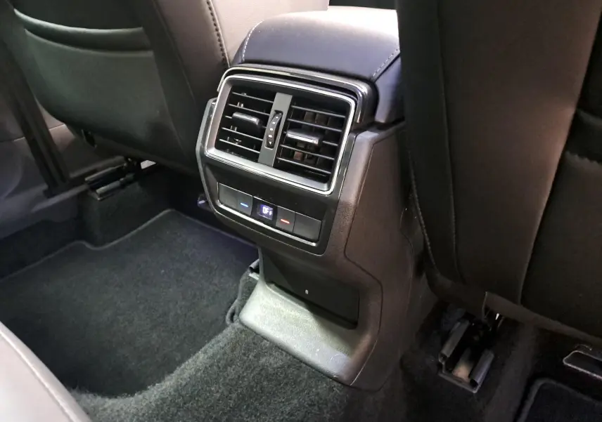 Vue rapprochée de la console arrière noire avec bouches d’aération et commandes de climatisation du Skoda Karoq 2023.
