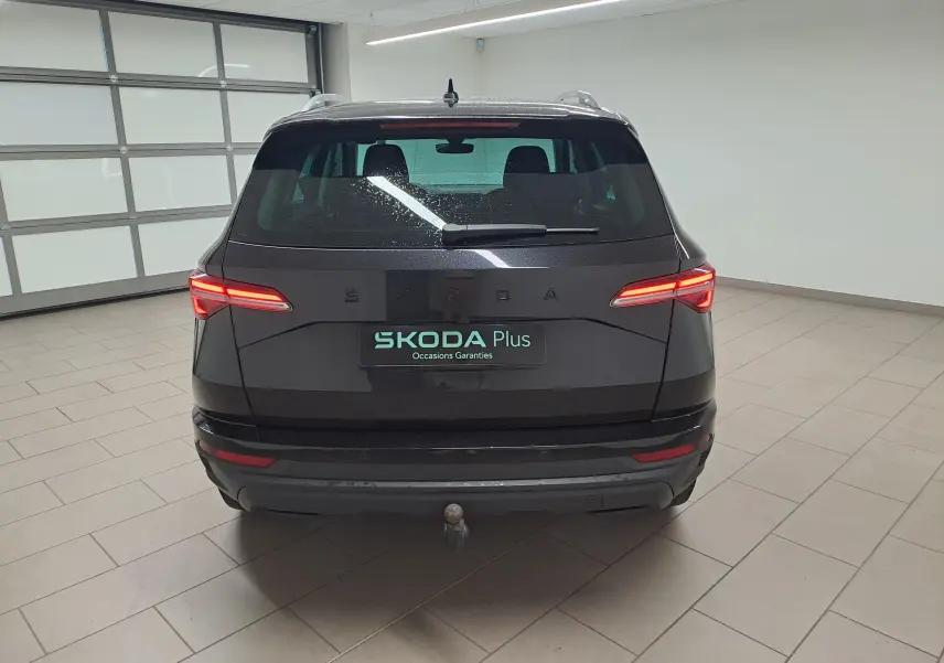 Vue arrière d'un Skoda Karoq noir Magic Nacré 2023 avec feux allumés et crochet d'attelage escamotable visible.