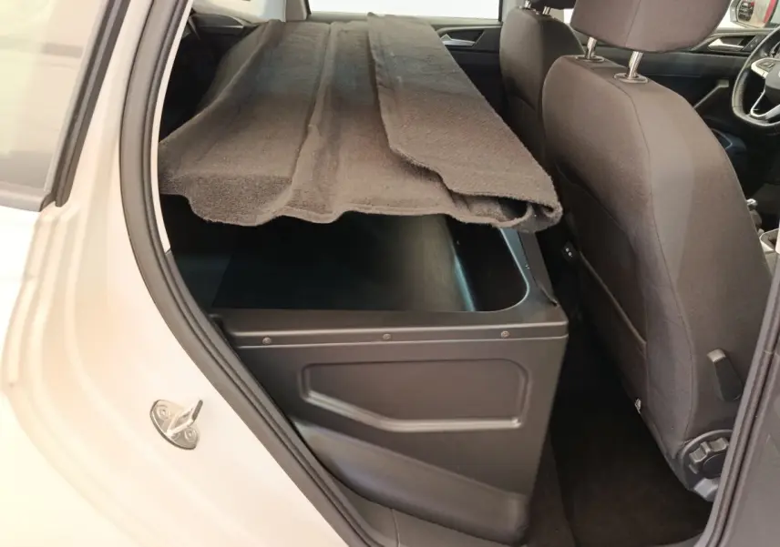 Vue intérieure côté arrière droit d'une Volkswagen Polo 2023 gris clair avec coffre de rangement sous la banquette arrière.