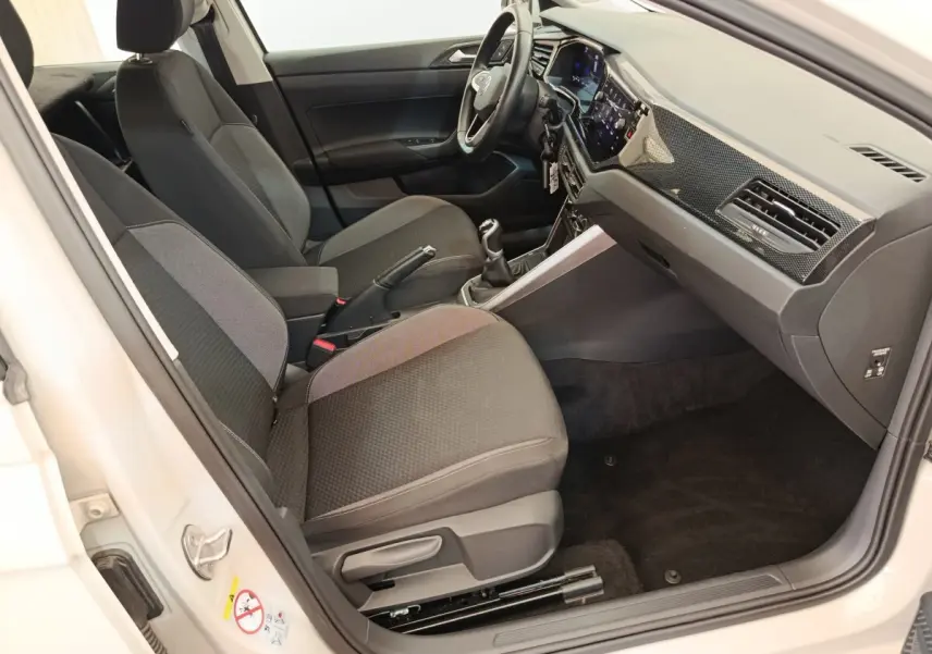 Intérieur avant droit de la Volkswagen Polo 2023, sièges gris foncé, volant multifonctions alu-cuir et tableau de bord digital.