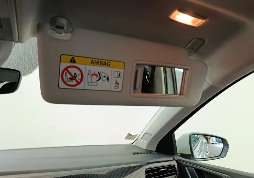 Vue intérieure côté passager du pare-soleil gris clair avec miroir et rétroviseur extérieur visible d’une Volkswagen Polo 2023.