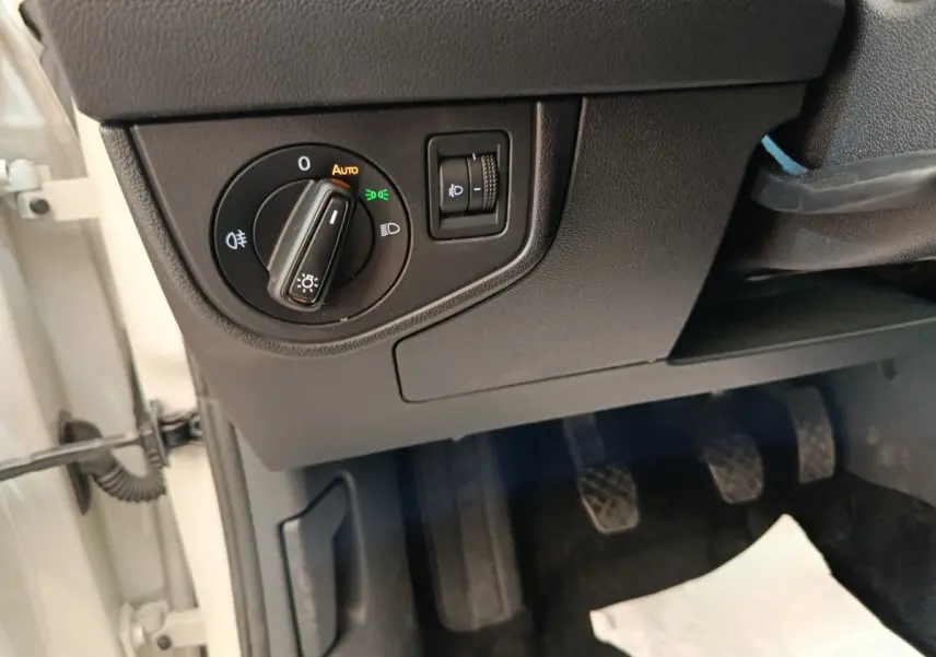 Vue rapprochée du tableau de bord côté gauche avec commande des phares et pédales d’une Volkswagen Polo gris clair 2023.