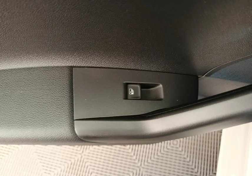 Gros plan sur le bouton de commande de la vitre électrique côté conducteur d'une Volkswagen Polo gris clair.