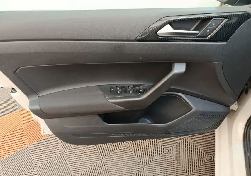 Vue intérieure côté gauche de la porte avant d'une Volkswagen Polo 2023, avec commandes électriques et poignée noire.