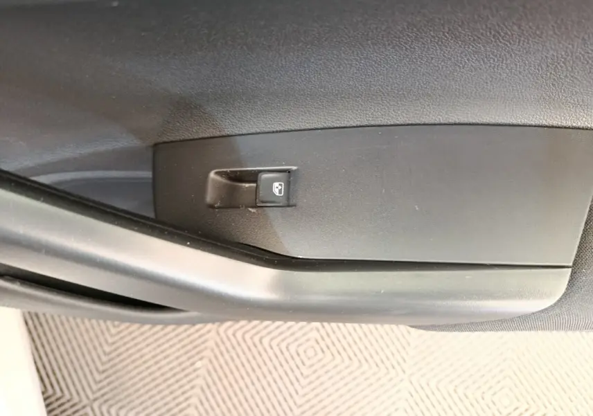 Gros plan sur le bouton de verrouillage centralisé sur la porte intérieure côté conducteur d'une Volkswagen Polo gris clair.
