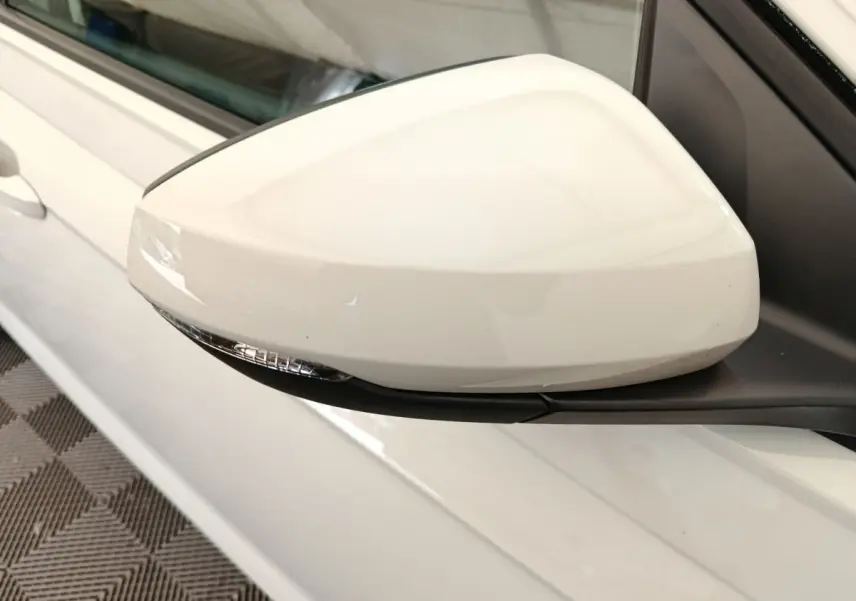 Gros plan sur le rétroviseur droit blanc d'une Volkswagen Polo 2023, avec clignotant intégré et carrosserie claire visible.