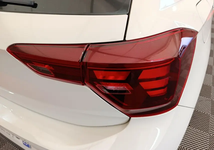 Gros plan sur le feu arrière droit rouge d'une Volkswagen Polo gris clair, avec partie de la carrosserie visible.