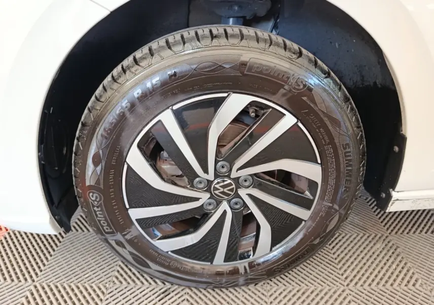 Gros plan sur la roue avant gauche d'une Volkswagen Polo gris clair avec jante alliage noir et argentée.
