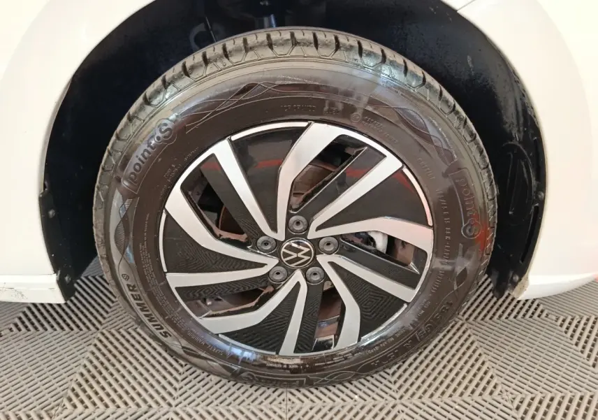 Gros plan sur la roue avant droite d'une Volkswagen Polo gris clair avec jante alliage noir et argent.