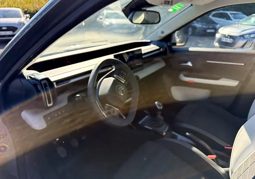 Vue intérieure côté conducteur de la Citroën C3 gris mercure, volant multifonction et levier de vitesses manuel visibles.