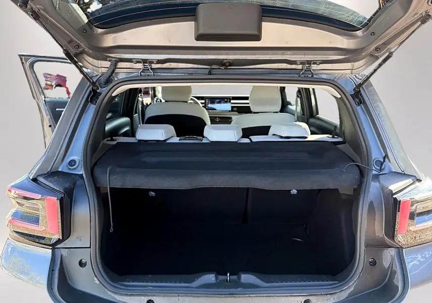 Vue arrière ouverte du coffre d'une Citroën C3 gris mercure, avec banquette arrière blanche et cache-bagages noir.