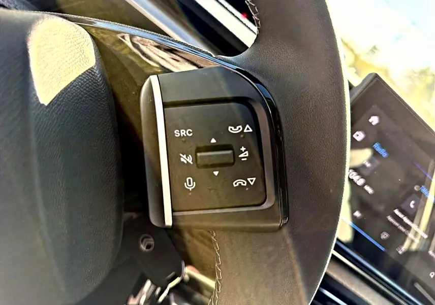 Gros plan sur les commandes audio au volant de la Citroën C3 2025, avec écran tactile en arrière-plan.