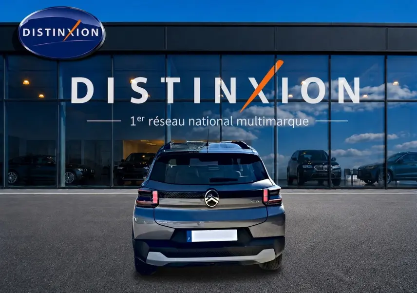 Vue arrière d'une Citroën C3 gris mercure garée devant une vitrine avec logo Distinxion.