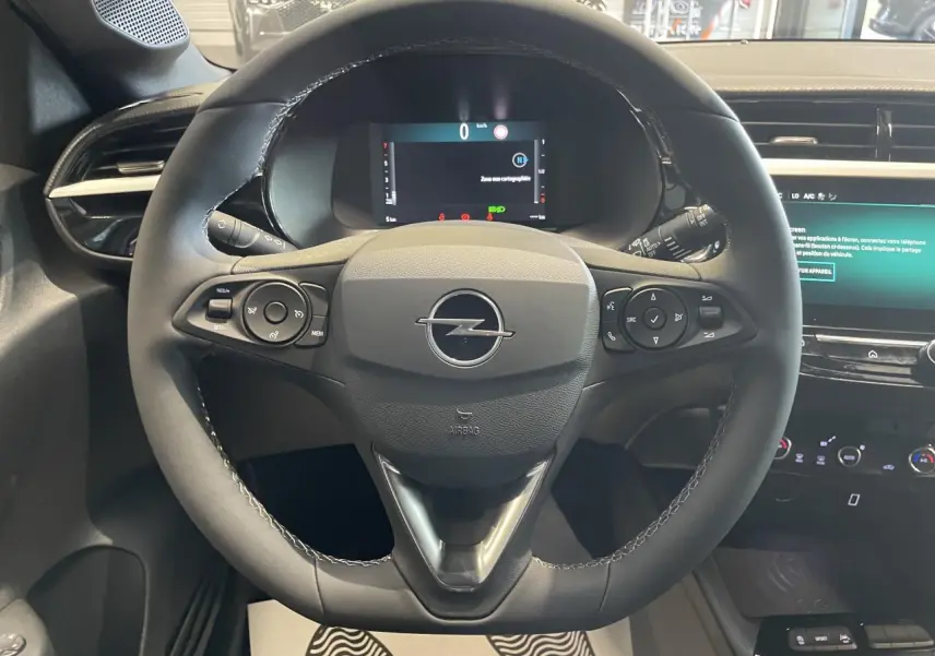 Vue rapprochée du volant noir en cuir synthétique d'une Opel Corsa 2026 avec tableau de bord numérique et écran tactile.