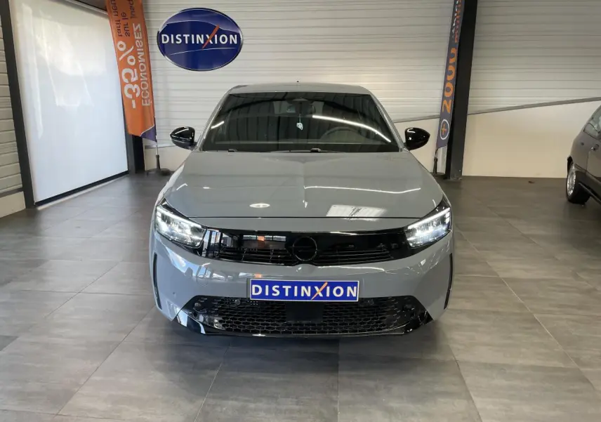 Vue frontale d'une Opel Corsa gris Grafik avec calandre noire et phares LED allumés en showroom.