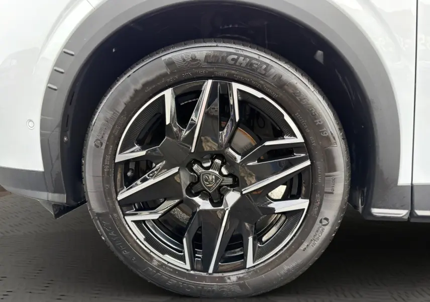 Gros plan sur la roue avant droite du Peugeot 3008 blanc, mettant en valeur la jante noire brillante au design moderne.