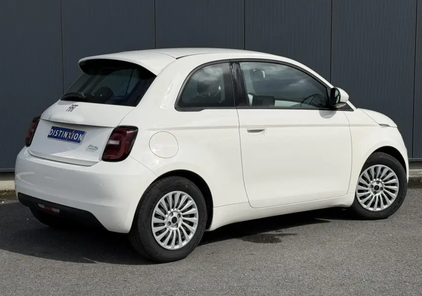 Vue 3/4 arrière droite d'une Fiat 500 électrique blanche Arctic avec jantes alu 16 pouces et feux arrière foncés.