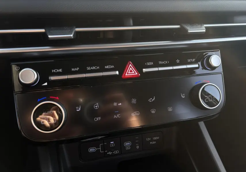 Vue rapprochée de la console centrale du Hyundai Tucson 2025, affichant les commandes tactiles et boutons de climatisation.