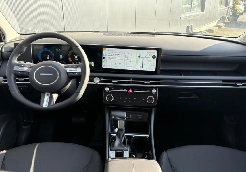 Intérieur du Hyundai Tucson 2025 vu de face, tableau de bord noir avec écran tactile large et volant cuir noir.