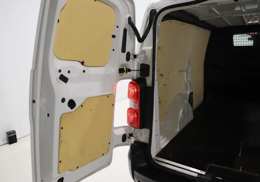 Vue intérieure arrière du fourgon blanc Citroën Jumpy XL 2019 avec portes ouvertes et aménagement bois visible.