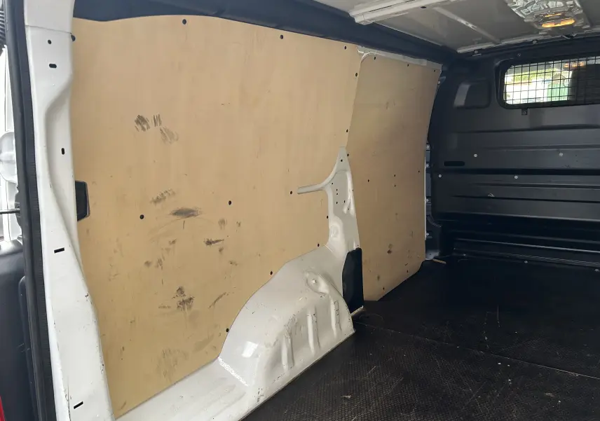 Vue intérieure du fourgon blanc Citroën Jumpy XL 2019, montrant la cloison bois et le plancher noir antidérapant.