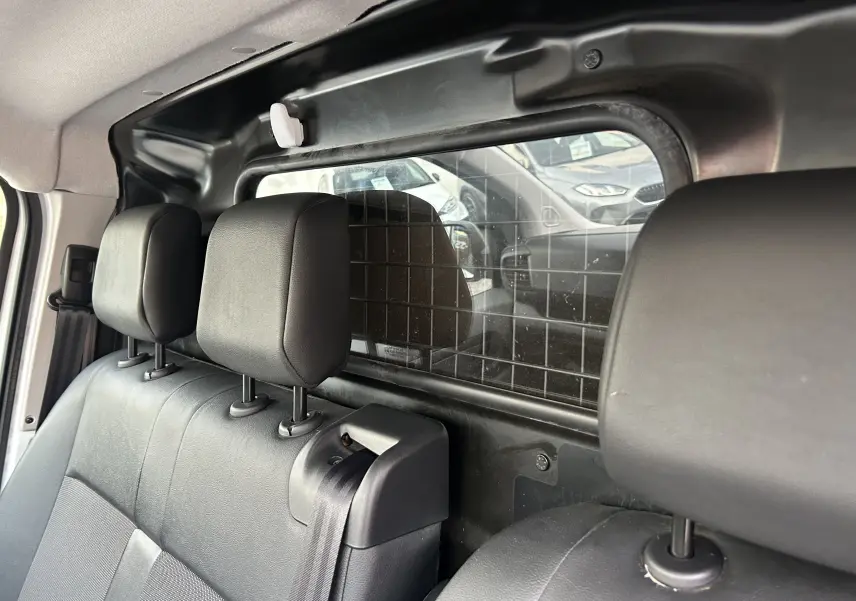 Vue intérieure arrière du Citroën Jumpy blanc, montrant la banquette avec appuie-têtes et séparation grillagée vers le coffre.